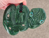 Green jade pendant with intricate carvings held by a hand on a neutral background