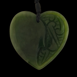 Heart-shaped green jade pendant with intricate carvings on a black background