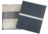 Woolen scarf and packaging with 'Made in New Zealand' text on a white background