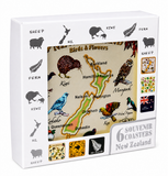 A boxed set of New Zealand souvenir coasters shown in its retail packaging. The white box features black silhouettes of sheep, kiwi, fern, and New Zealand maps, with a central inset showing a vintage-style birds and flowers map of New Zealand.