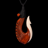 Carved bone fish hook pendant on a black background