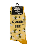 A pair of yellow crew socks with a bee pattern and the words 'QUEEN BEE' printed on them, packaged in a black hanger sleeve .
