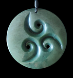 Greenstone pendant with spiral design on a black background