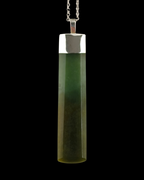 A cylindrical pendant necklace made of a translucent greenstone with a polished silver cap and chain, shown against a solid black background.