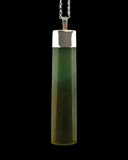 A cylindrical pendant necklace made of a translucent greenstone with a polished silver cap and chain, shown against a solid black background.