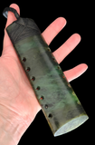 Hand holding a greenstone with holes on a black background