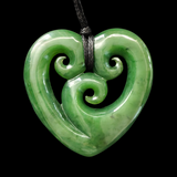 Greenstone heart-shaped pendant with spiral design on a black background