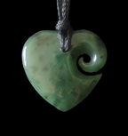 Heart-shaped greenstone pendant with a spiral design on a black background