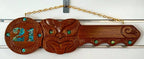A wooden 21st key carving with Paua inlay, hanging against a white background.
